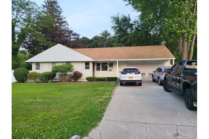 View of front of property featuring an attached garage, driveway, and a front lawn