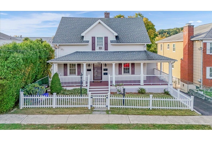 View of front of home featuring a porch, roof with shingles, a gate, a fenced front yard, and a chimney