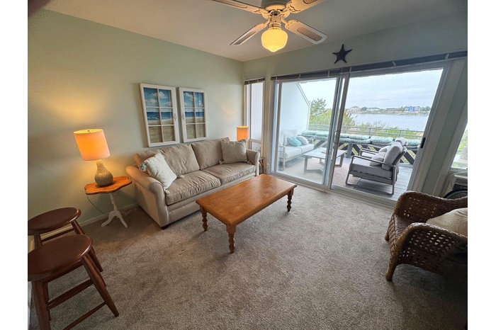 Carpeted living area with a water view, ceiling fan, and baseboards
