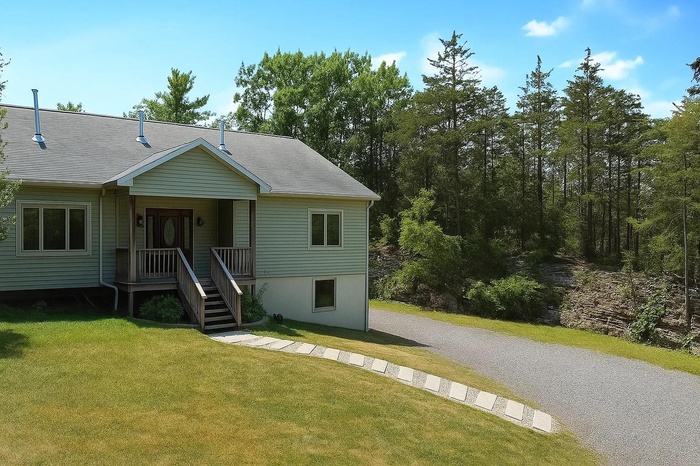 View of front of house featuring a front lawn and roof with shingles