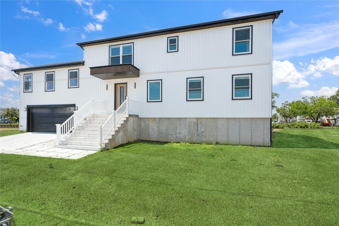 View of front of property featuring an attached garage, concrete driveway, and a front yard