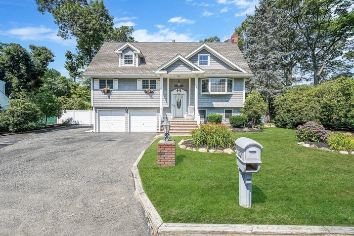 Bi-level home featuring asphalt driveway, a garage, and a chimney