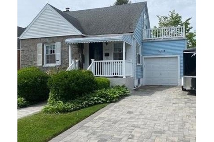 View of front of home featuring a porch, decorative driveway, stone siding, and a balcony