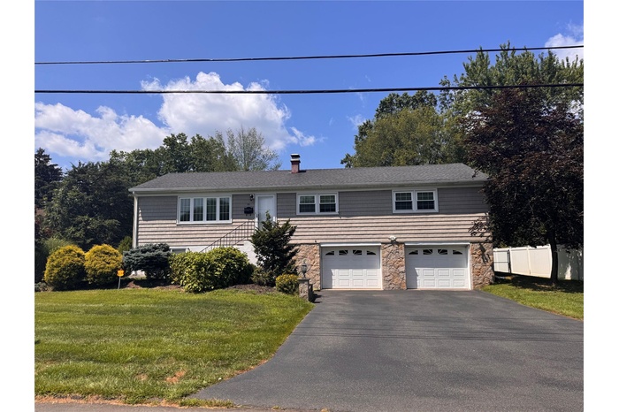 View of front of property featuring a garage, driveway, and stone siding