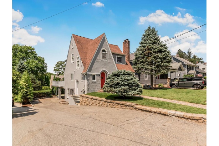 View of front of house with a chimney, stucco siding, a front lawn, a shingled roof, and concrete driveway