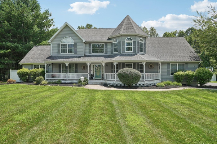 Victorian-style house featuring roof with shingles, covered porch, and a front lawn