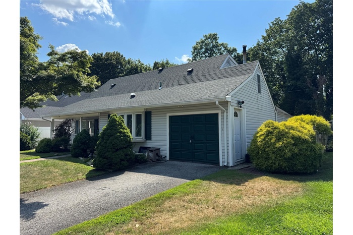 View of front of home featuring a garage, roof with shingles, asphalt driveway, and a front lawn