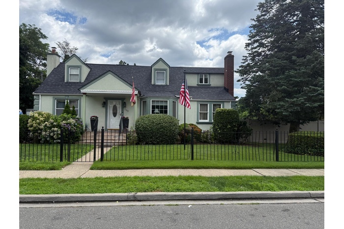 View of front of property featuring a chimney, stucco siding, a fenced front yard, and a shingled roof
