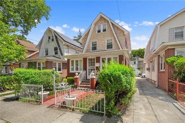 Dutch colonial with a fenced front yard, a gambrel roof, and brick siding