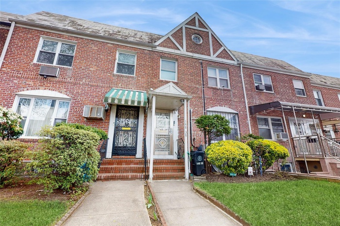Townhome / multi-family property with brick siding, cooling unit, and a wall mounted air conditioner