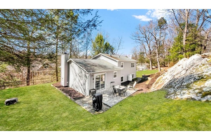 Rear view of property featuring a yard, a patio area, fence, and a chimney