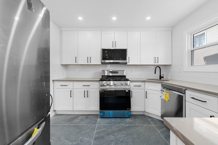 Kitchen featuring stainless steel appliances, light countertops, white cabinetry, and recessed lighting