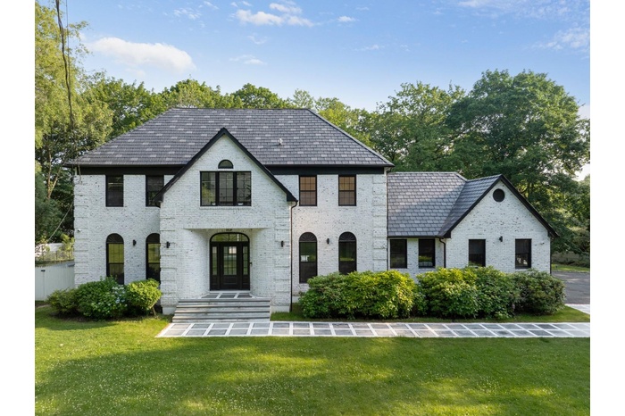 French country inspired facade featuring a high end roof, brick siding, and a front yard