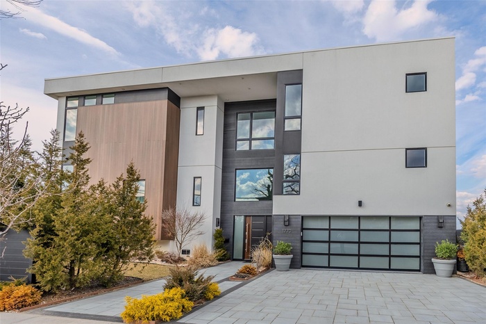 Modern home with decorative driveway, a garage, and stucco siding