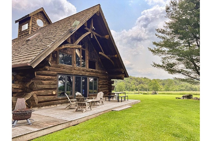 Rear view of house featuring a fire pit, a deck, a lawn, and log exterior