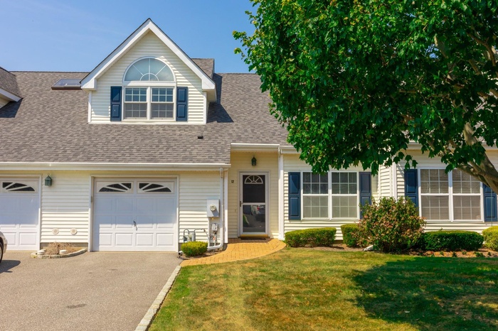View of front of property with driveway, a front lawn, a shingled roof, and a garage