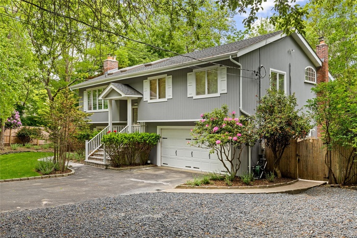 Hi-Ranch with a chimney, driveway, an attached garage, and a shingled roof