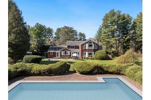 Welcome to this stately columned brick and shingle Colonial, nestled amidst lush landscaping that perfectly complements its timeless architectural elegance within the esteemed Village of Old Brookville.