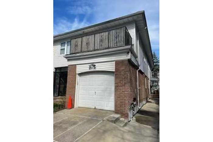 View of property exterior featuring an attached garage, a balcony, brick siding, and concrete driveway