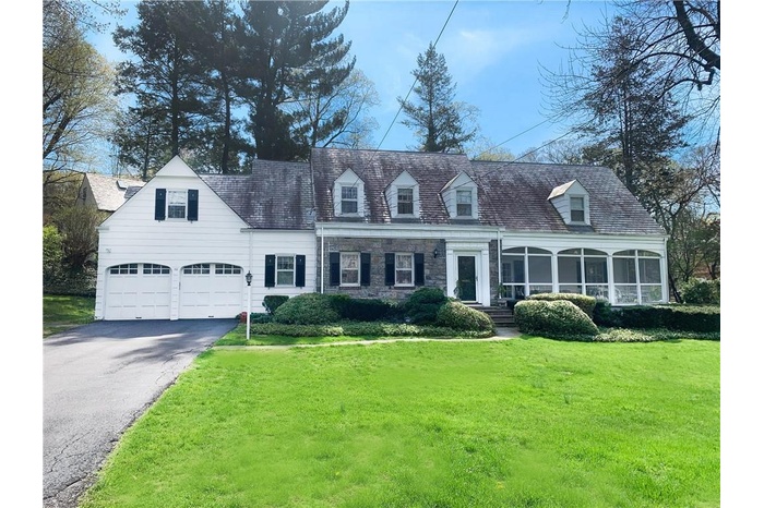 Cape cod home featuring asphalt driveway, a front lawn, and a sunroom