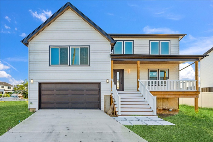 View of front of property featuring a porch, concrete driveway, an attached garage, stairway, and a front lawn