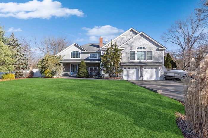 Shingle-style home with a chimney, a garage, asphalt driveway, and a front yard