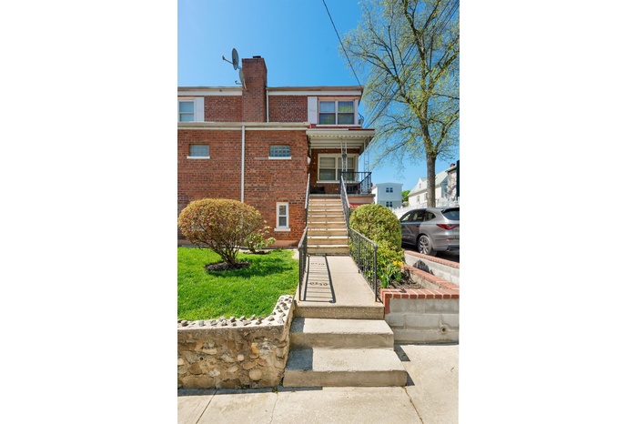 View of front of property featuring stairway, brick siding, a chimney, and covered porch