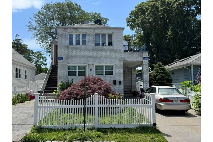 View of front of property featuring stairs, a fenced front yard, brick siding, and driveway