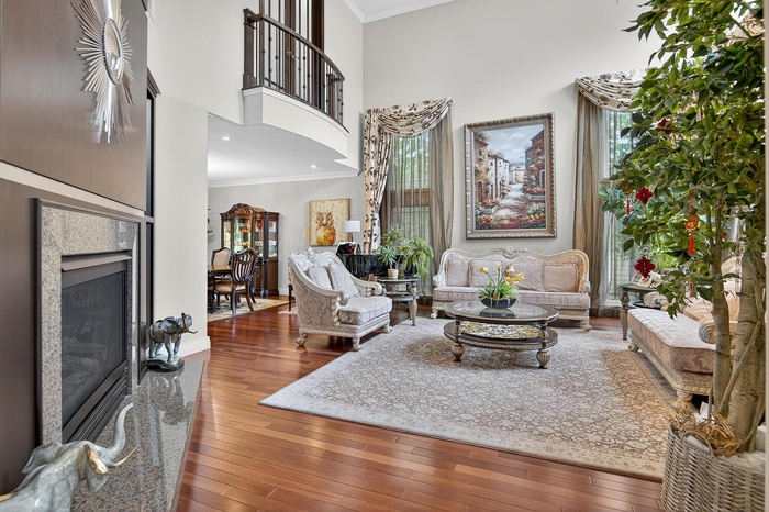 Living room with crown molding, wood-type flooring, a premium fireplace, and a high ceiling