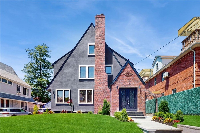 English style home featuring stucco siding, a chimney, a front lawn, and french doors