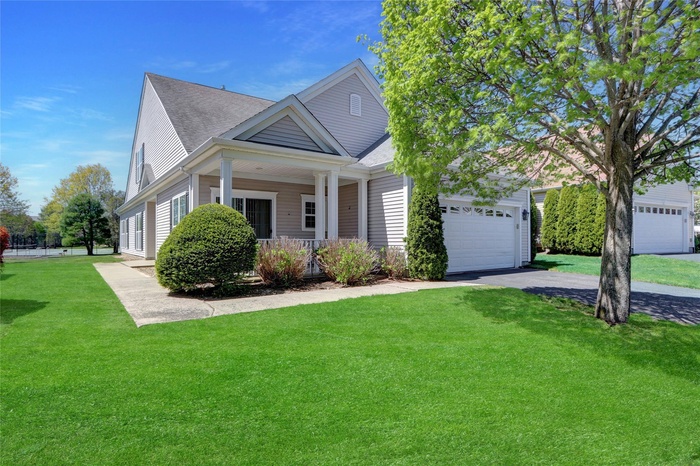 View of front of home featuring roof with shingles, a front yard, a porch, and aphalt driveway