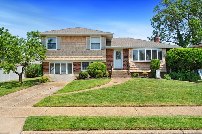 Split level home with a chimney and roof with shingles