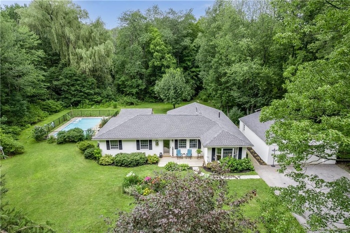 View of front of home with a front lawn, a porch, and a pool