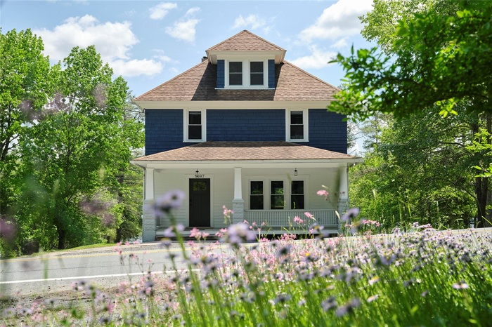 View of front of house featuring covered porch and roof with shingles