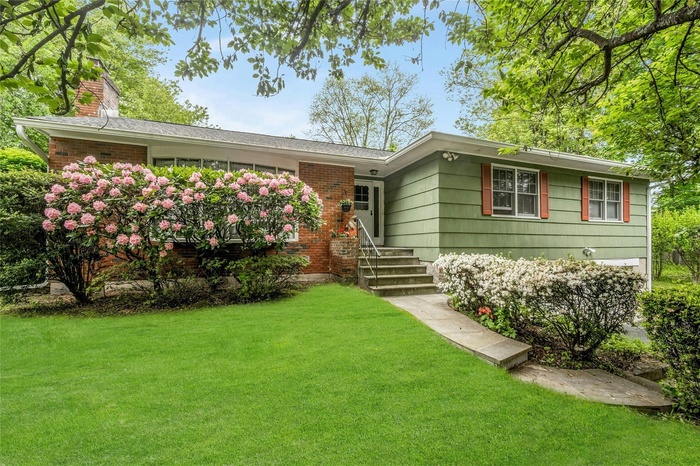 Ranch-style home with a front lawn, a chimney, and brick siding