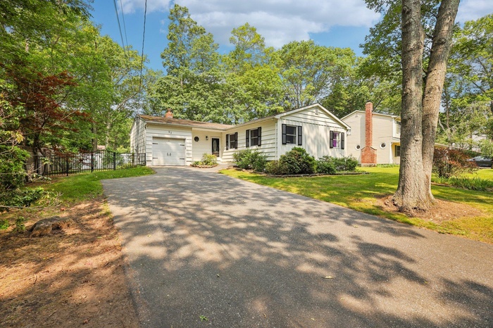 View of front of property featuring driveway, a garage, a chimney, and board and batten siding
