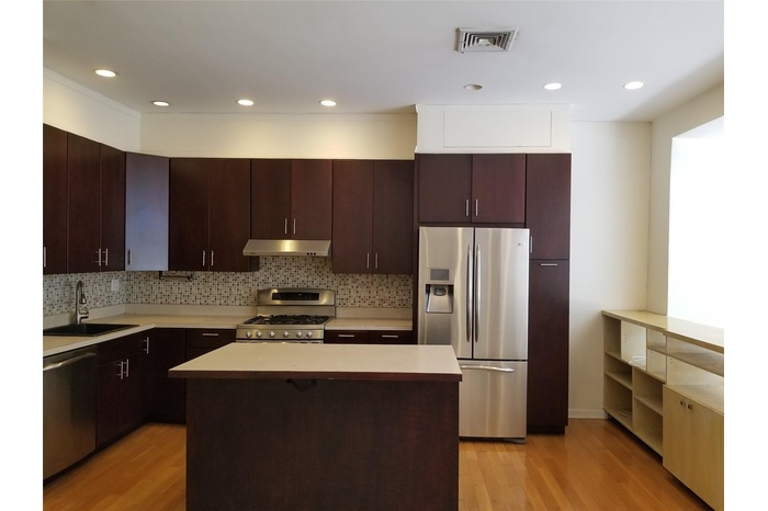 Kitchen featuring stainless steel appliances, decorative backsplash, light wood-style floors, recessed lighting, and a center island