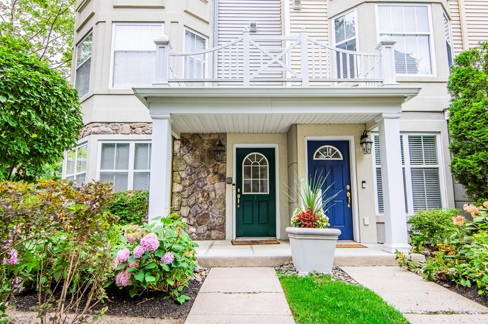 Property entrance with a balcony, stone siding, and covered porch