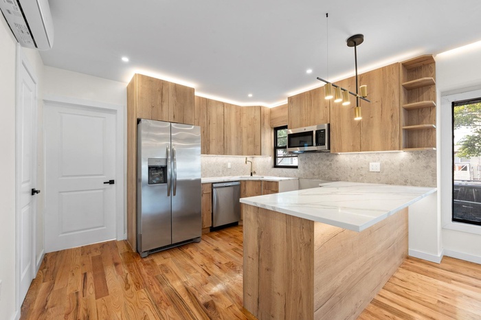 Kitchen with stainless steel appliances, a wall unit AC, backsplash, light wood-style flooring, and recessed lighting