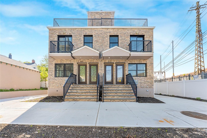 View of front of property with fence, brick siding, and a balcony