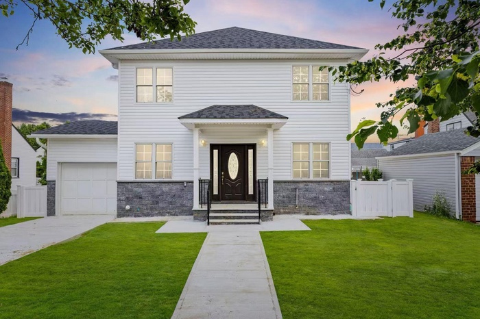 View of front of house with an attached garage, stone siding, concrete driveway, and roof with shingles