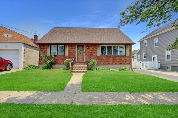 View of front of property featuring brick siding, a shingled roof, and a gate