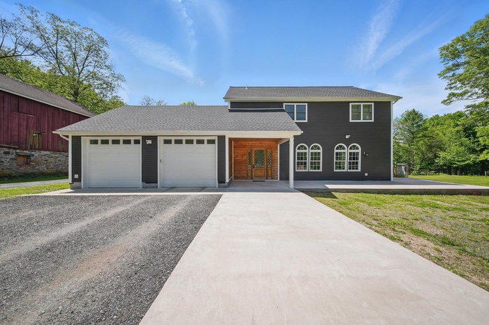 Traditional-style house with gravel driveway, an attached garage, and roof with shingles