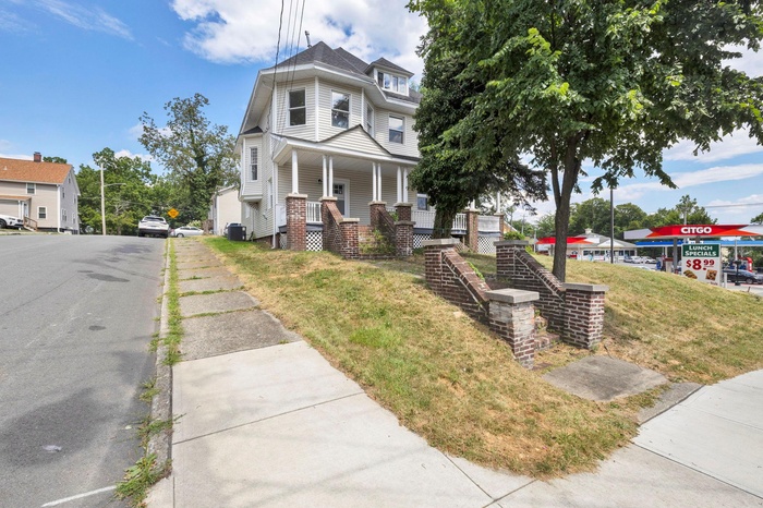Victorian-style house with covered porch and a front lawn