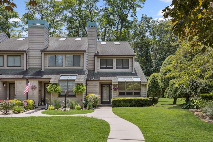 View of front of home with a chimney, a shingled roof, and a front yard