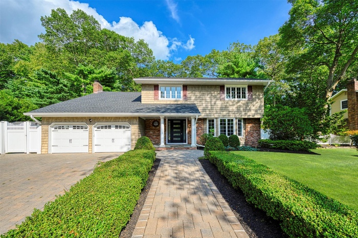 View of front of house with a garage, a chimney, driveway, a shingled roof, and brick siding