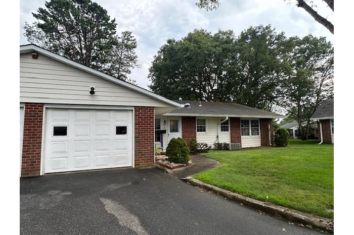 Ranch-style home featuring brick siding, asphalt driveway, a front yard, and a garage