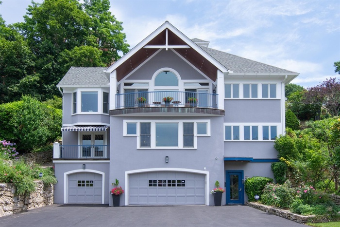 View of front of house featuring a balcony, stucco siding, an attached garage, asphalt driveway, and a shingled roof