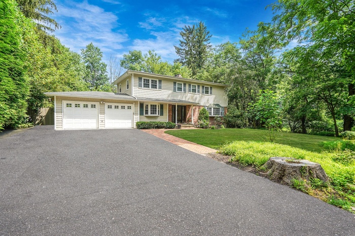 View of front facade featuring a garage, asphalt driveway, and a front lawn