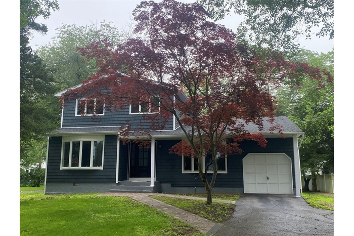 View of front facade with a front lawn, driveway, and a garage